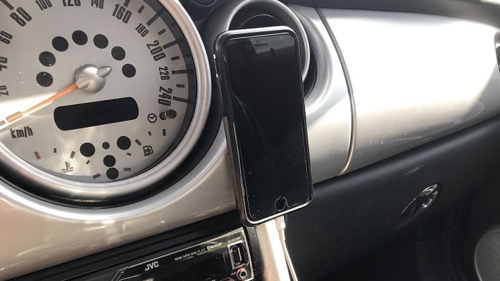 Ein Smartphone wird in einer Auto-Handyhalterung mit einfachem Klettverschluss an das Armaturenbrett befestigt.