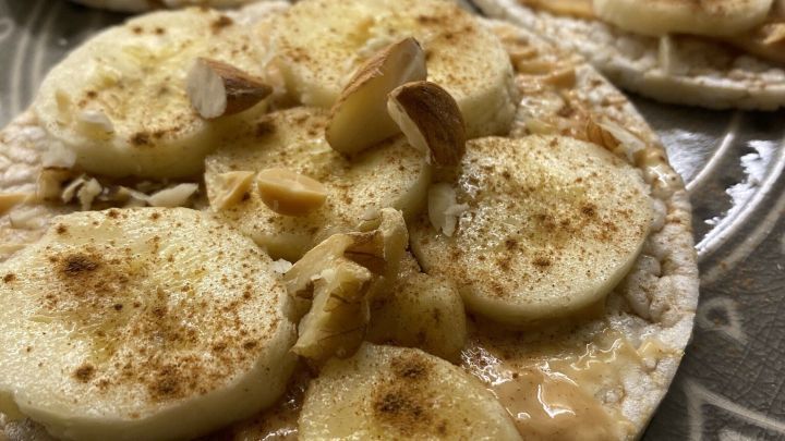 Gesunde Reiswaffeln mit Bananen und N&uuml;ssen liegen appetitlich auf einem dekorativen Teller, bereit zum Snacks w&auml;hrend des Netflixens.