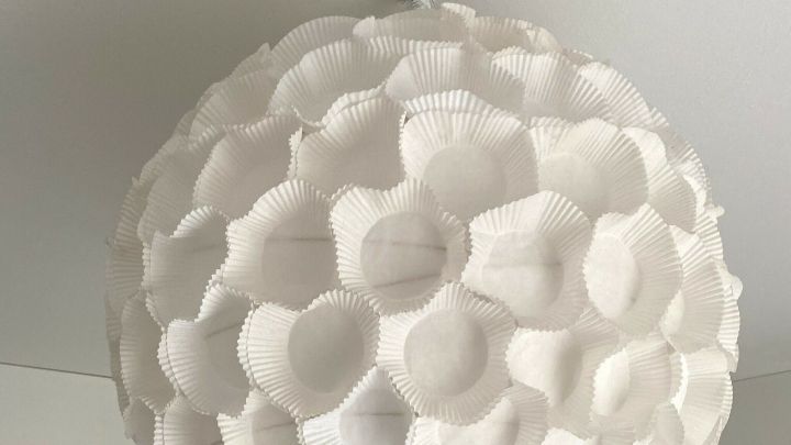 Eine gro&szlig;e, runde Ikea-Regolit-Lampe schwebt im Raum und beleuchtet mit ihrem einzigartigen Design den modernen Innenbereich.