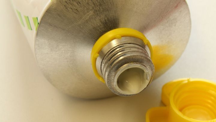 Eine Tube mit gelbem Deckel steht auf einem Tisch und zeigt ihre &Ouml;ffnung, bereit zur Anwendung gegen Kopfl&auml;use.