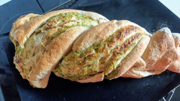 Ein gezwirbeltes K&auml;se-Kr&auml;uter-Grillbrot liegt auf einem Backblech, frisch gebacken und leicht goldbraun, bereit zum Servieren.