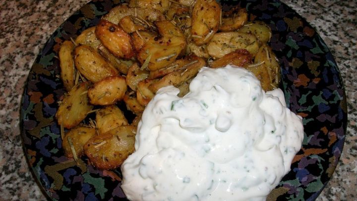 Krosse Rosmarin-Drillingskartoffeln liegen auf einem Teller neben cremigem Schnittlauch-Quark, dekorativ angerichtet.