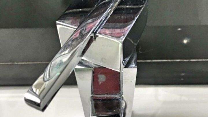 Ein gl&auml;nzender Wasserhahn steht auf einem Waschbecken, im Badezimmer, bereit, Wasser zum Sp&uuml;len zu aktivieren.