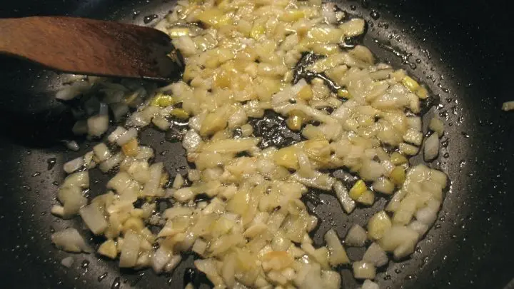 In einer gro&szlig;en Pfanne wird das &Ouml;l erhitzt und darin Zwiebelw&uuml;rfel und Knoblauch kurz angebraten.