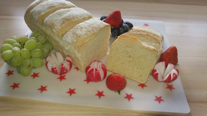 Ein frisch gebackenes Toastbrot liegt auf einem Teller, umgeben von Trauben und dekoriert mit Erdbeeren und Bonbons.