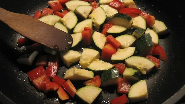 Die Hälfte der Paprika-Zucchini-Stücke werden in einer hohen beschichteten Pfanne im heißen Öl kurz angebraten.