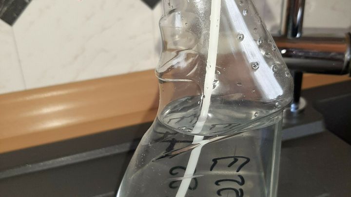Eine Flasche mit Reinigungsmittel steht auf einer Ablage, bereit zum Reinigen von stumpfem, fleckigem Laminat.