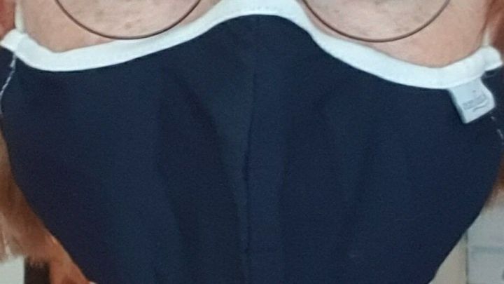 Ein Brillentr&auml;ger tr&auml;gt eine dunkle Mund- und Nasenmaske, die gut sitzt und die Brille nicht beschl&auml;gt.