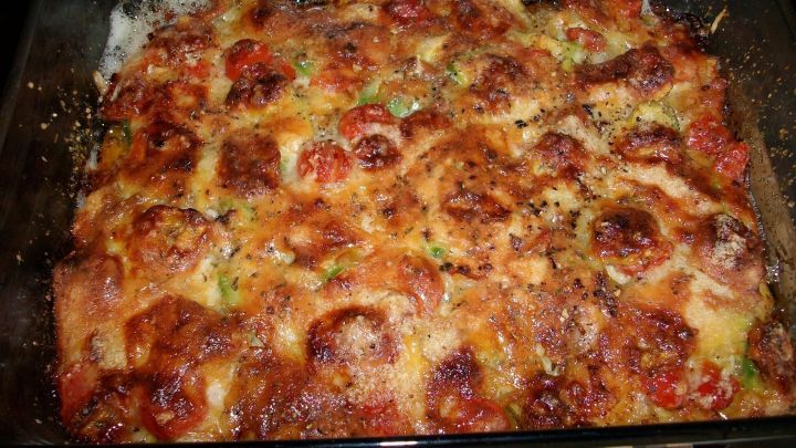 Ein goldbrauner Maultaschen-Avocado-Auflauf, &uuml;berbacken mit K&auml;se, liegt in einer Glasauflaufform und duftet lecker.