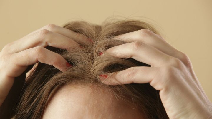 H&auml;nde massieren sanft das Haar am Kopf, w&auml;hrend der Hintergrund in einem warmen Farbton gehalten ist, passend zu Naturkosmetik.