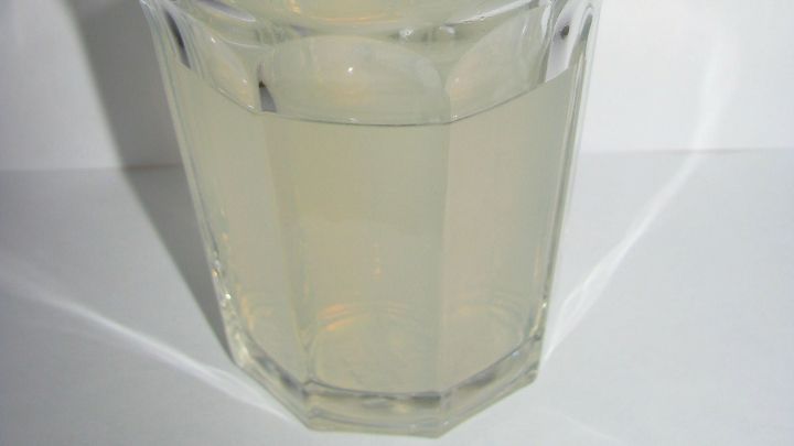 Ein transparentes Glas mit kalorienarmem, leicht tr&uuml;bem Sommergetr&auml;nk steht auf einem wei&szlig;en Tisch.