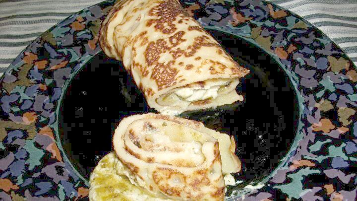 Pfannkuchen liegen auf einem bunten Teller, gef&uuml;llt mit einer Mischung aus Zutaten und serviert mit Walnuss-Basilikum-Pesto.