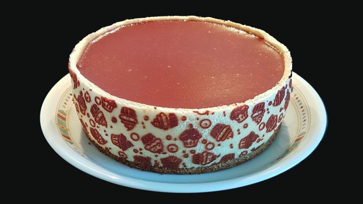 Ein runder, dekorativ pr&auml;gnanter Biskuit liegt auf einem wei&szlig;en Teller, umgeben von dunklem Hintergrund.