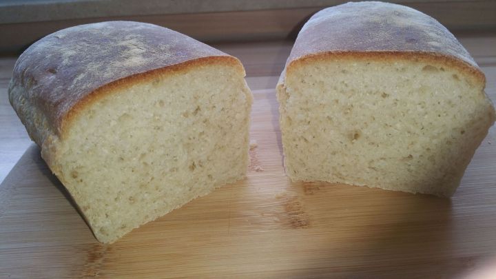 Ein frisch gebackenes Toastbrot mit weicher Kruste liegt auf einem Holzbrett, aufgeschnitten und bereit zum Servieren.
