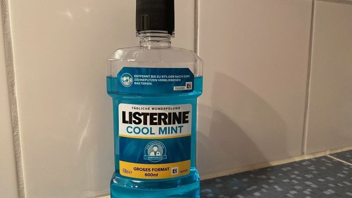 Eine Flasche Mundwasser steht auf einer Fliese im Badezimmer, bereit zur Anwendung f&uuml;r frischen Atem und bessere Mundhygiene.