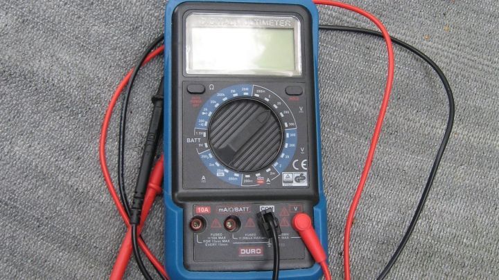 Ein Multimeter liegt auf einem grauen Untergrund, w&auml;hrend es mit elektrischen Testleitungen verbunden ist, um Messungen durchzuf&uuml;hren.