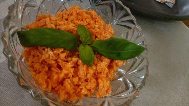 Ein Glaskelch mit Karottensalat, garniert mit frischem Basilikum, steht auf einem Tisch mit maritimen Accessoires.