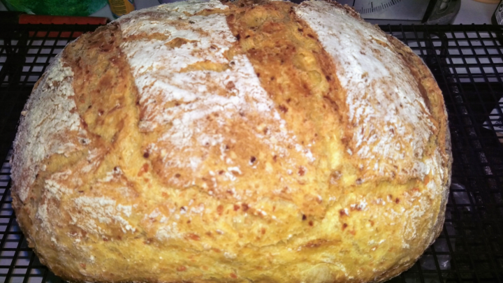 Ein frisch gebackenes Karottenbrot liegt auf einem Kuchengitter und zeigt eine goldbraune, knusprige Kruste.
