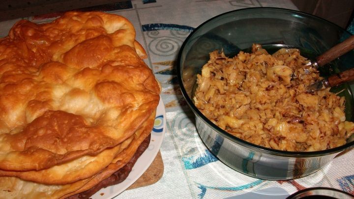 Pfannab&auml;uscht liegt auf einem Teller neben einer Sch&uuml;ssel mit Krautsalat, umgeben von einer neutralen Tischdecke.