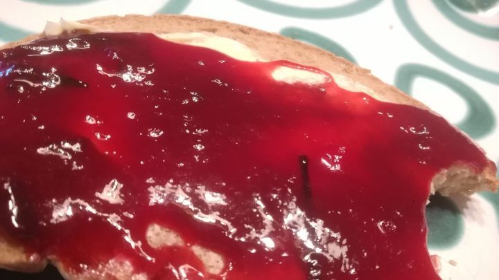 Ein St&uuml;ck Brot mit Zwetschgenkonfit&uuml;re ist appetitlich angerichtet auf einem bunten, spiralf&ouml;rmigen Teller.