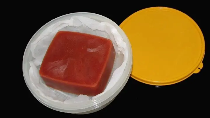 Die Gefrierdose mit dem Tomateneisklotz kurz in lauwarmes Wasser tauchen - so flutscht er super raus - in das ausgeschlagene Sieb geben.