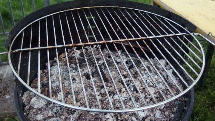 Ein Grillrost steht &uuml;ber gl&uuml;hender Kohle, bereit zum Reinigen mit Salat&ouml;l oder Zeitungspapier im Freien.