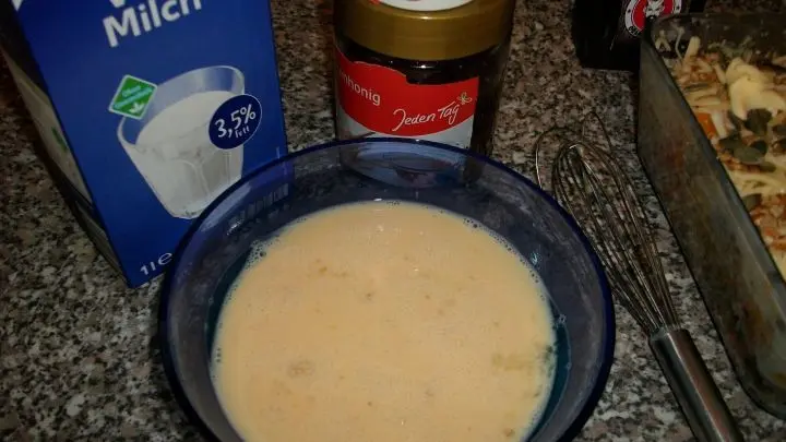 In einer kleinen Sch&uuml;ssel die Milch, 3 ganze Eier, etwas Knoblauchpulver nach Geschmack und einen TL Honig mit einem Schneebesen kurz aufschlagen und gleichm&auml;&szlig;ig &uuml;ber den Auflauf leeren.