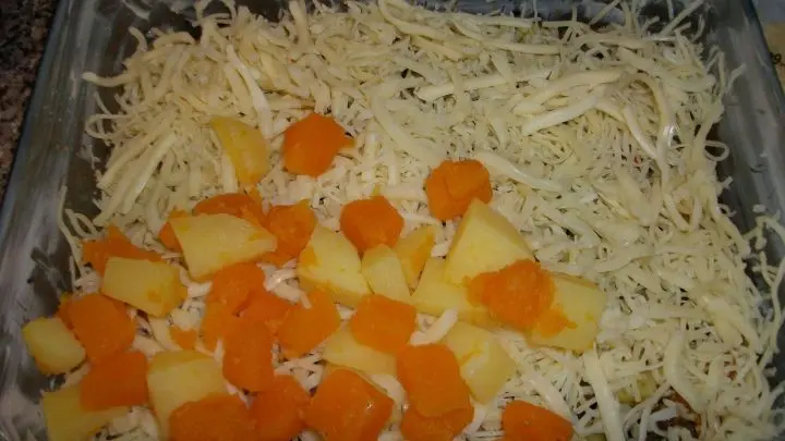 Die H&auml;lfte von jedem der drei K&auml;sesorten dr&uuml;ber schichten und eine weitere Schicht Kartoffeln und K&uuml;rbis. 