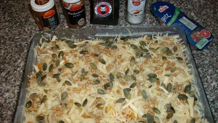 Zum Schluss noch noch die K&uuml;rbiskerne und den Sonnenblumenkerne-Mix dr&uuml;ber streuen und ein paar Butterfl&ouml;ckchen darauf verteilen.