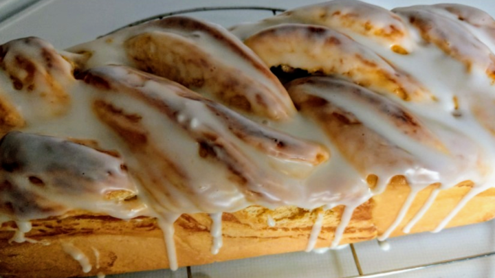 Ein frisch gebackener Quark-Hefezopf mit einer gl&auml;nzenden Zuckerglasur auf einem Kuchengitter.