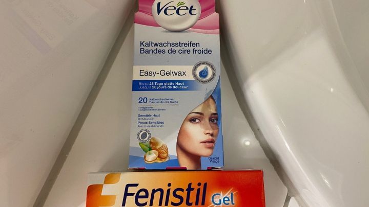 Eine Verpackung mit Veet Kaltwachsstreifen steht neben Fenistil Gel, um Hautirritationen nach dem Waxing zu vermeiden.