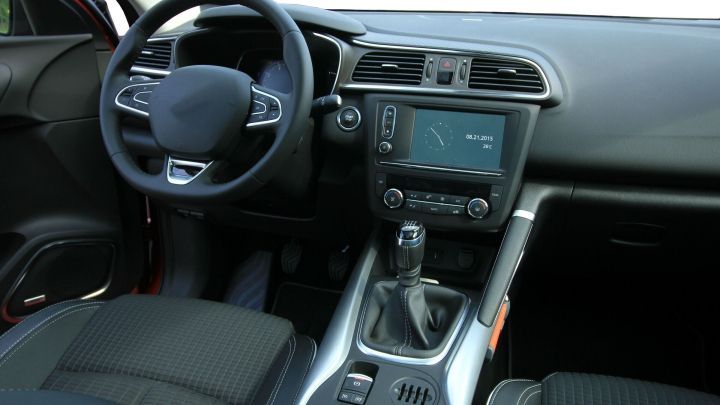 Das Armaturenbrett des Autos zeigt das Steuer und ein modernes Infotainment-System im Innenraum.