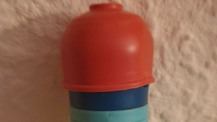 Ein Wischer mit einem blauen Griff und einer roten Kappe steht an einer Texturwand, bereit zum Einsatz und rutscht nicht mehr weg.