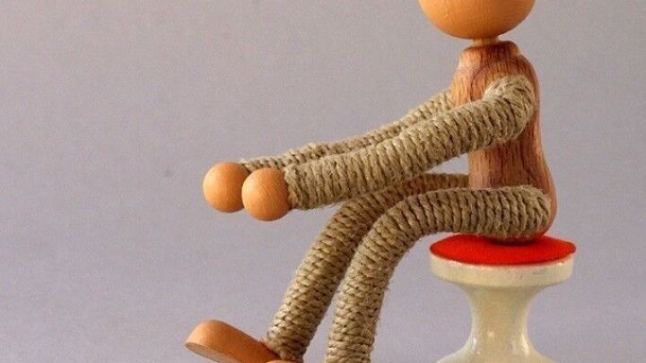 Eine Figur sitzt auf einem kleinen Hocker und deutet eine angespannte Haltung an, passend zum Thema Gefahr bei Verstopfung.