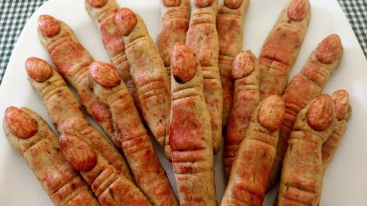 Knusprige Hexenfinger in Form von Keksen liegen auf einem wei&szlig;en Teller - perfekt f&uuml;r Halloween-Dekoration und Snacks.