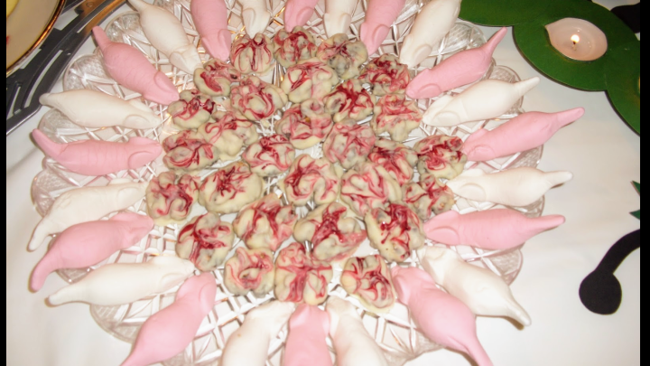 Eine Platte mit M&auml;usegeb&auml;ck in rosa und wei&szlig;en Farben ist kunstvoll angeordnet, ideal f&uuml;r eine Halloween-Feier.