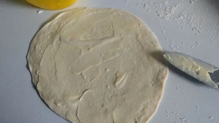 Die Teigkreise dünn mit der weichen Butter bestreichen. Bitte die Butter nicht verflüssigen. Zimmerweich reicht aus.