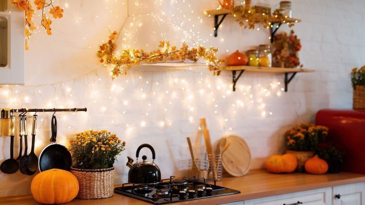 Eine gem&uuml;tliche K&uuml;che mit einer neuen Gasher stove hat herbstliche Dekorationen, K&uuml;rbisse und Lichterketten, die strahlen.