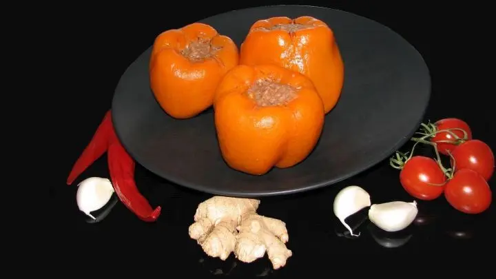 Hier die befüllten Paprika auf einem Teller, damit kein Saft verloren geht.
