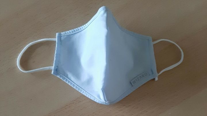 Zwei Nasen-Mund-Sch&uuml;tze liegen auf einem Tisch, eine einfarbig hellblau, die andere mit Leopardenmuster, bereit zum K&uuml;rzen und Anpassen.