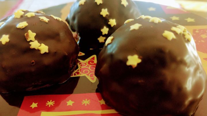 Dunkle Lebkuchenberge mit goldenen Sternen dekoriert stehen auf einem bunten Untergrund mit Weihnachtsmotiven.