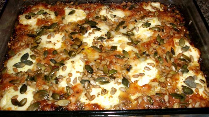 Ein Auflauf mit goldbraunem K&auml;se und ger&ouml;steten Kernen ist frisch gebacken und im Glasbeh&auml;lter serviert.