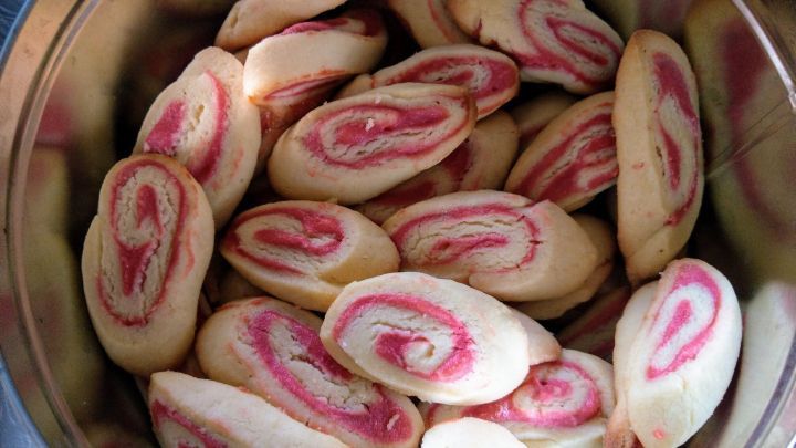 Zarte Marzipan-Himbeerschnecken liegen &uuml;ppig in einer Metalldose und verleihen dem Raum einen s&uuml;&szlig;en Duft.