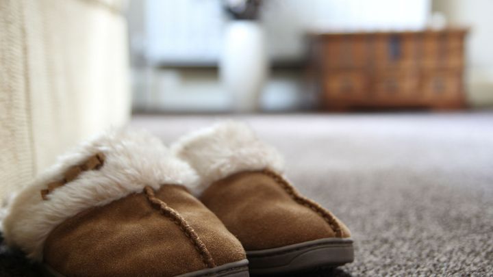 Braune Hausschuhe liegen auf einem Teppich, bereit zum Tragen, um den Raum zu versch&ouml;nern und Komfort zu bieten.