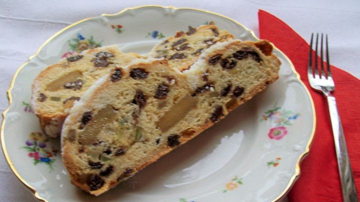 Auf einem eleganten, blumenverzierten Teller liegen zwei Scheiben von Christstollen mit Marzipan und Trockenfr&uuml;chten.