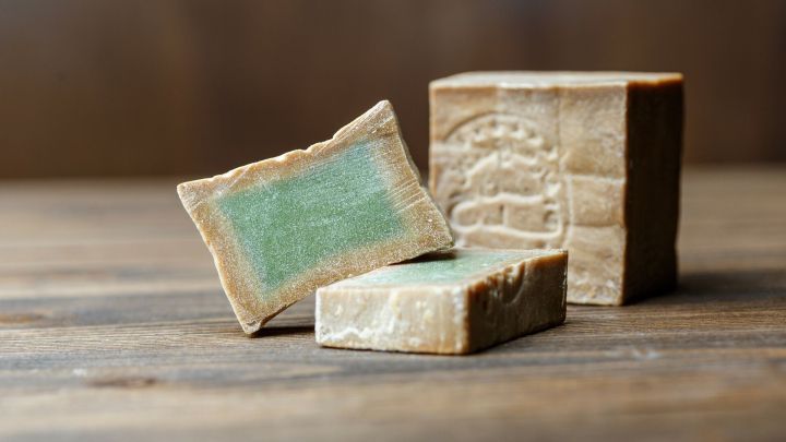 Nat&uuml;rliche Seifenst&uuml;cke liegen auf einem Holztisch, perfekt zum L&ouml;sen von trockener juckender Haut nach dem Duschen.