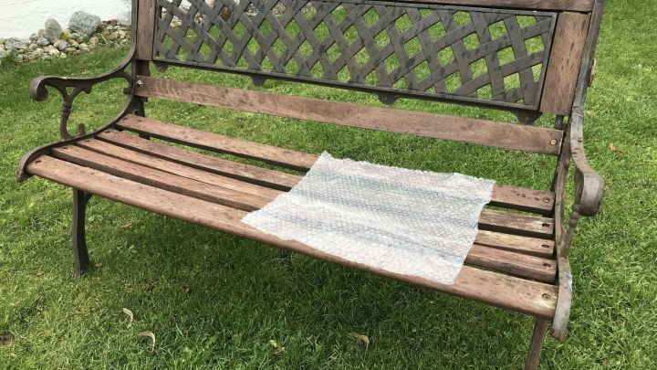 Auf einer Holzbank im Garten liegt Luftpolsterfolie als Sitzunterlage, um den Komfort im Freien zu erh&ouml;hen.