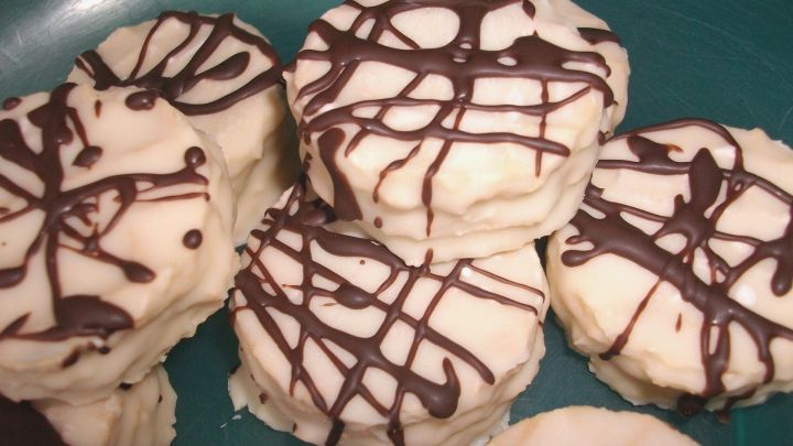 Kleine Waffeln aus wei&szlig;er Schokolade sind auf einem gr&uuml;nen Teller gestapelt, mit Schokoladendekor verziert.