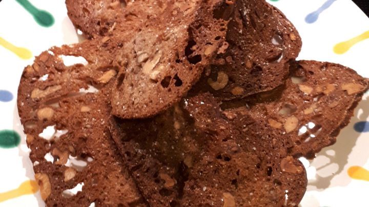 Auf dem bunten Teller liegen knusprige Brotschips, die aus altem Brot hergestellt wurden und appetitlich aussehen.