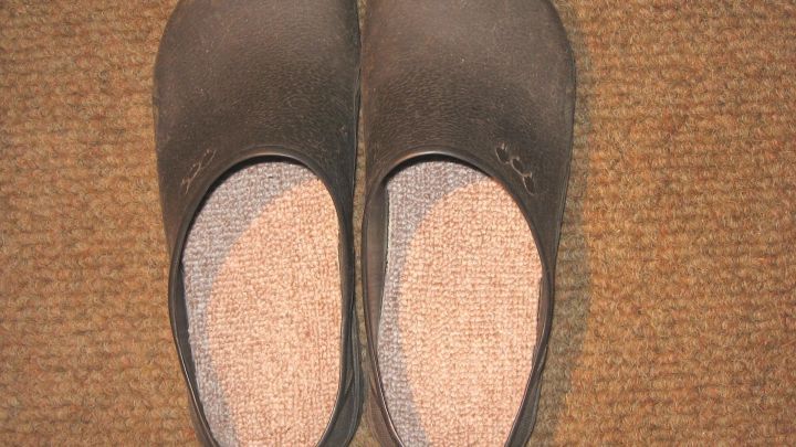 Schwarze Einlegesohlen liegen flach auf einem Teppich, bereit, in die Hausschuhe eingelegt zu werden.